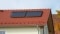 La imagen muestra el tejado de una casa roja sobre el que se ha montado un colector solar térmico.