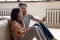 Una pareja feliz está sentada frente a un sistema de calefacción y sostiene un smartphone.