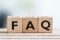 La imagen muestra tres cubos con las letras F, A y Q, que significan "Preguntas frecuentes".